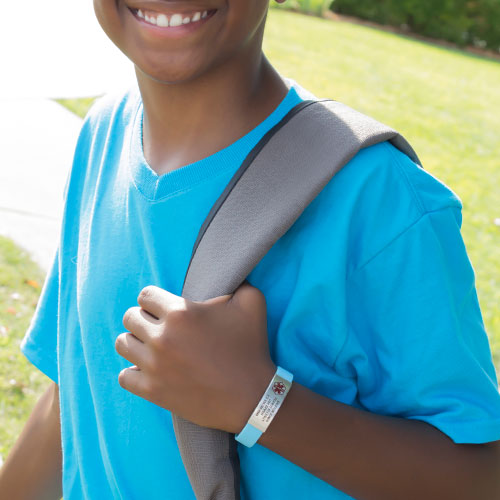 Boy in blue shirt wearing backpack and light blue silicone medical ID bracelet with custom engraving