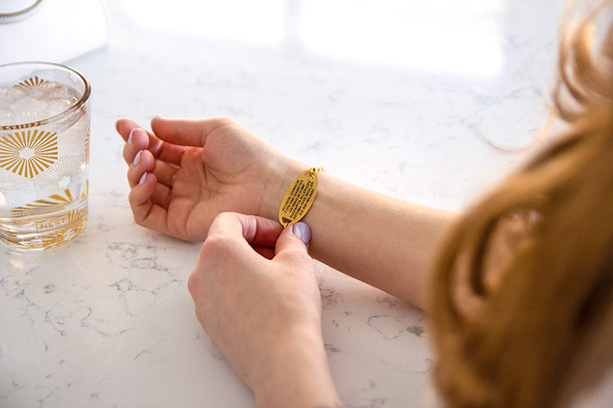 Woman showing gold tone custom laser engraved medical ID tag