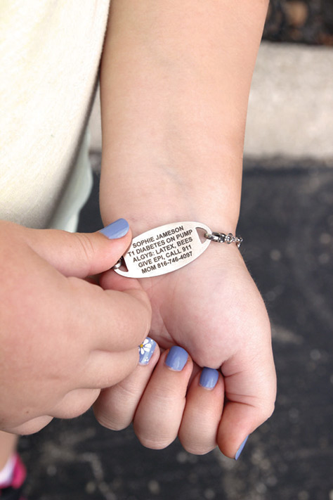 Young girl showing custom laser engraving on medical ID tag